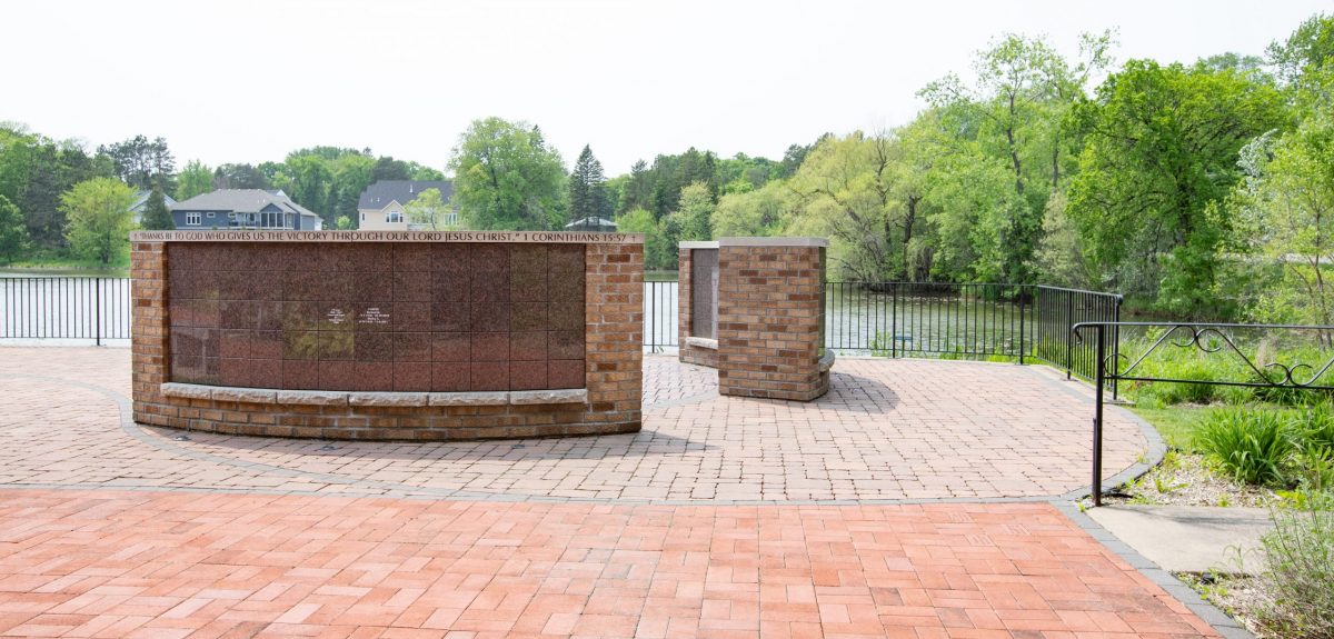 The backside of a curved columbarium wall showcases an inscription of 1 Corinthians 15:57 on its capstone.