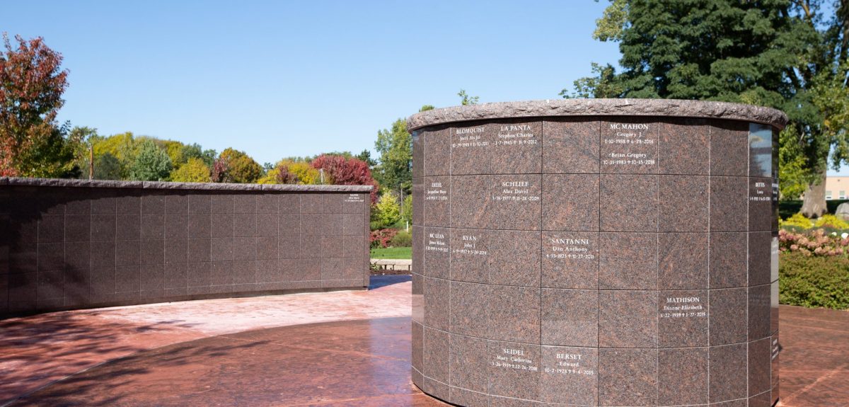 A York columbarium with multiple inscriptions sits across from a radiused columbarium wall atop a rich, red, concrete pad.
