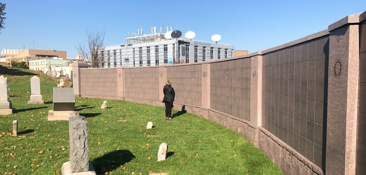 A woman admires a curved wall columbarium that sits on the edge of a cemetery.