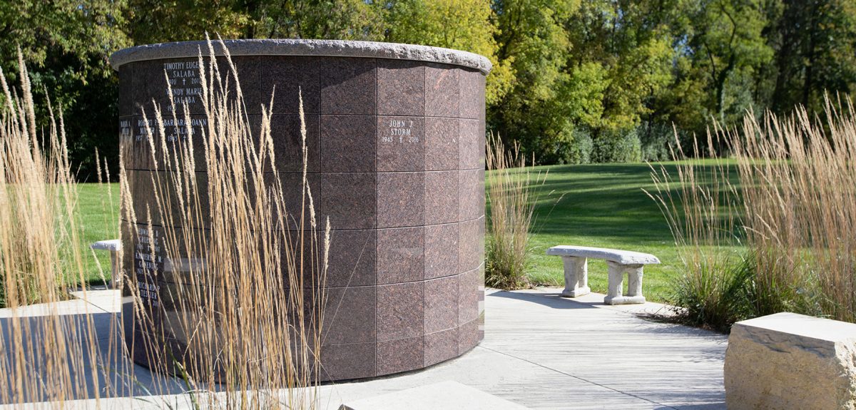 The sun illuminates one side of a York columbarium and draws long shadows from nearby benches and plantings.