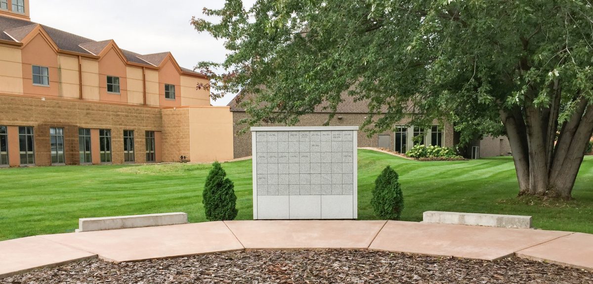 A foundation for future columbarium phases sits on both sides of a columbarium wall under large shade tree.